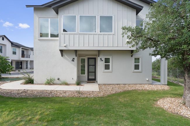 View of front of property featuring board and batten siding, a front yard, and stucco siding | Image 5