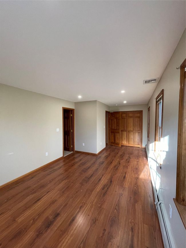 Room with a baseboard heating unit, dark wood-style floors, baseboards, visible vents, and recessed lighting | Image 13