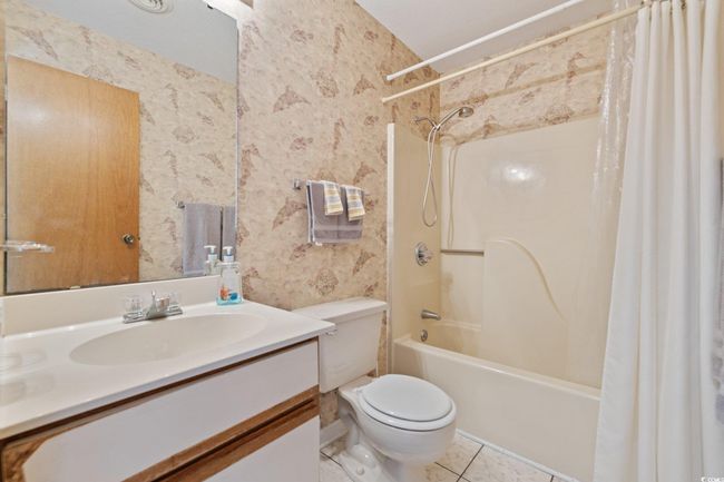 Bathroom featuring wallpapered walls, shower / bath combo with shower curtain, vanity, toilet, and tile patterned flooring | Image 10
