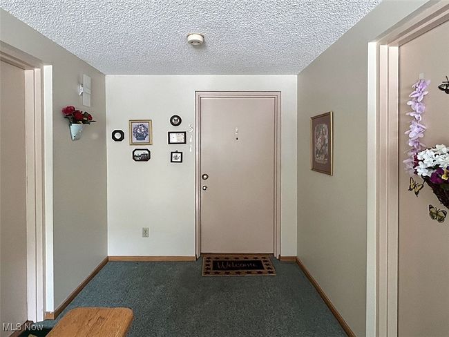 Doorway to hallway with carpet and a textured ceiling | Image 22