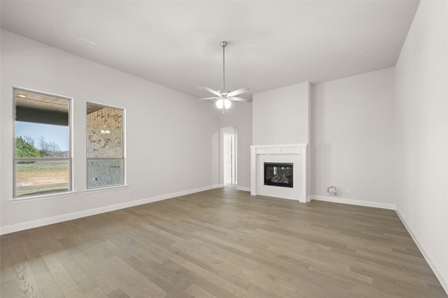Unfurnished living room featuring wood finished floors, a tile fireplace, and baseboards | Image 10