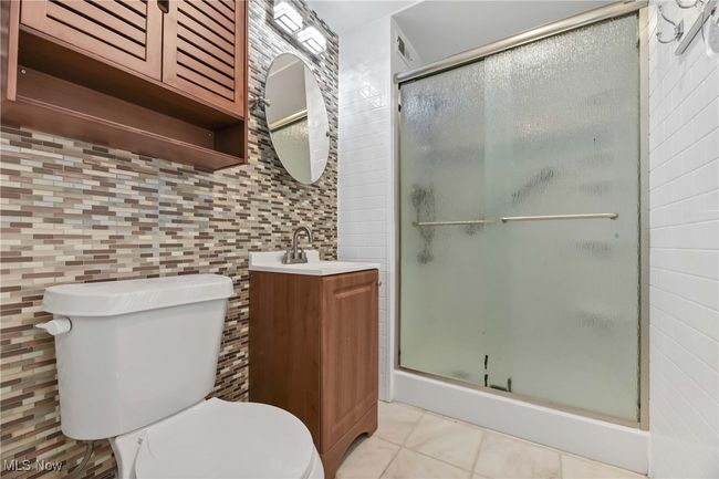 Bathroom featuring a shower stall, tile walls, toilet, tile patterned floors, and vanity | Image 18