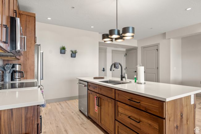 Kitchen featuring a sink, brown cabinets, light wood-style flooring, baseboards, and light countertops | Image 59