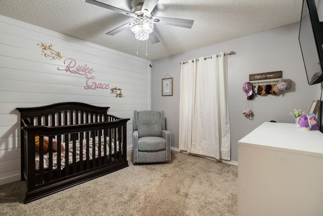 Carpeted bedroom with a nursery area, a textured ceiling, and a ceiling fan | Image 13