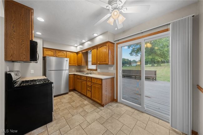 Kitchen with black appliances, ceiling fan, and sink | Image 9