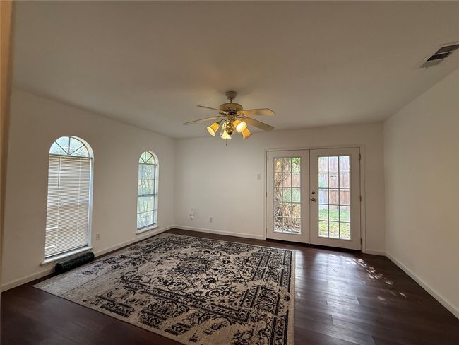 Empty room with dark wood-type flooring, a ceiling fan, and french doors | Image 12