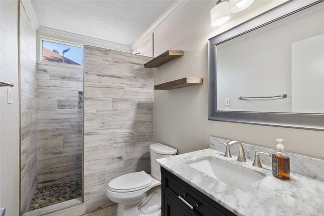 Full bath featuring a tile shower, toilet, vanity, crown molding, and a textured ceiling | Image 18