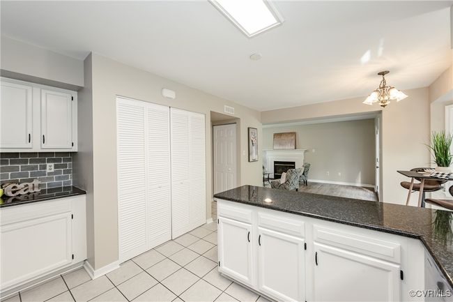 Kitchen featuring open floor plan, a glass covered fireplace, backsplash, white cabinetry, and visible vents | Image 10