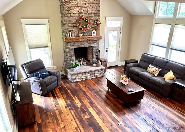 Living room featuring lofted ceiling, reclaimed oak wood-style floors, and a fireplace | Image 37