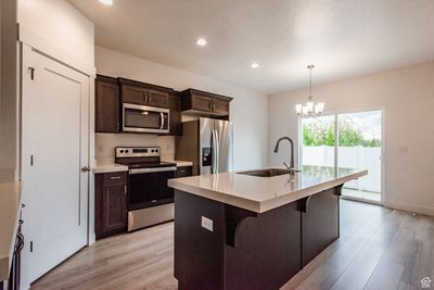 Kitchen featuring a center island with sink, stainless steel appliances, sink, and light hardwood / wood-style flooring | Image 3