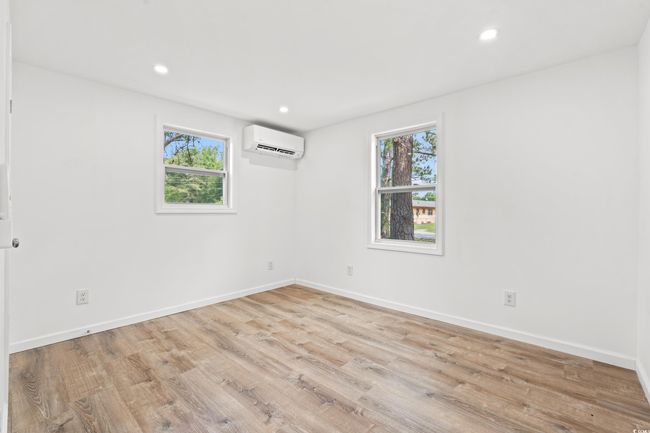 Spare room with a wall mounted AC, plenty of natural light, wood finished floors, baseboards, and recessed lighting | Image 13