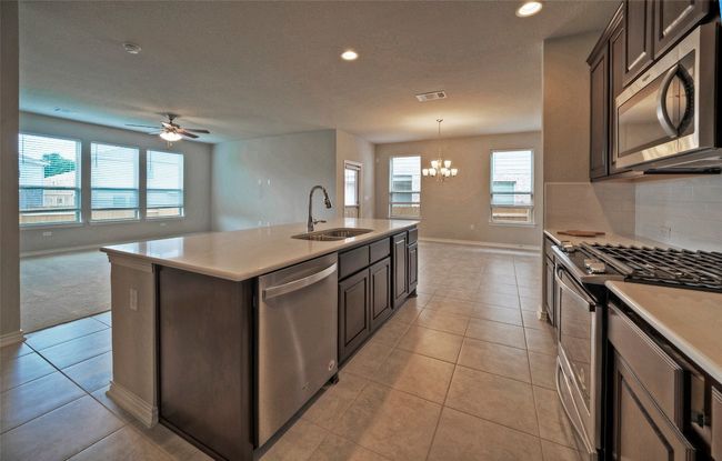 Kitchen with light tile patterned floors, a sink, ceiling fan with notable chandelier, and appliances with stainless steel finishes | Image 11