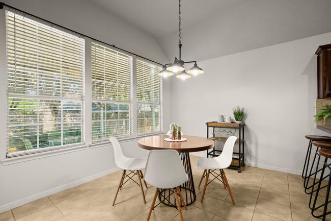 Dining area with lofted ceiling, light tile patterned floors, and a chandelier | Image 13