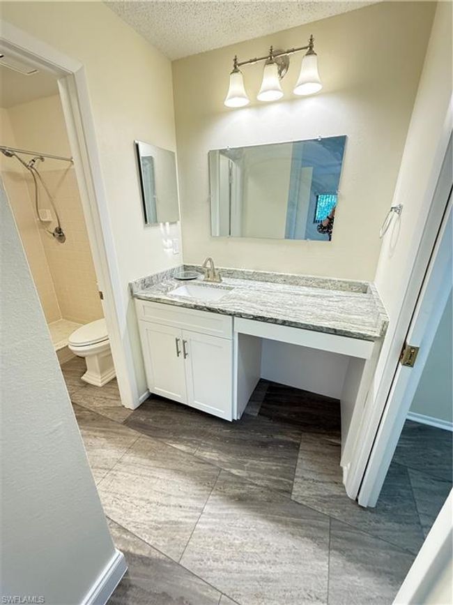 Full bath featuring a tile shower, toilet, vanity, and a textured ceiling | Image 15