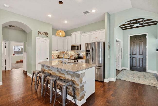 Kitchen featuring appliances with stainless steel finishes, dark wood-style floors, light stone counters, white cabinetry, and recessed lighting | Image 12
