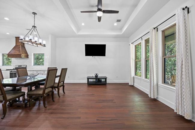 Dining room featuring dark wood-style flooring, a raised ceiling, recessed lighting, ceiling fan, and a​​‌​​​​‌​​‌‌​‌‌​​​‌‌​​‌‌​‌​​​​​‌ chandelier | Image 12
