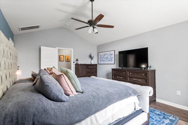 Bedroom with lofted ceiling, wood laminate floors, baseboards, and a ceiling fan | Image 17
