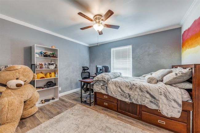 Bedroom featuring wood finished floors, crown molding, an office area, and ceiling fan | Image 19