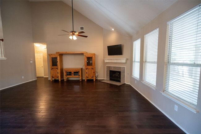living room with a tile fireplace, a ceiling fan, dark wood-style floors, and high vaulted ceiling | Image 7