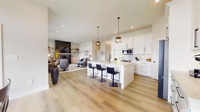 Kitchen with appliances with stainless steel finishes, a kitchen breakfast bar, open floor plan, white cabinetry, and recessed lighting | Image 10