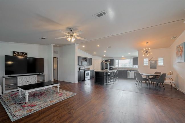 The living room features elegant cabinetry and stylish hardwood flooring that will make you feel right at home. Enjoy cozy evenings by the fireplace or entertain guests around the chic table in the heart of this vibrant space. | Image 8