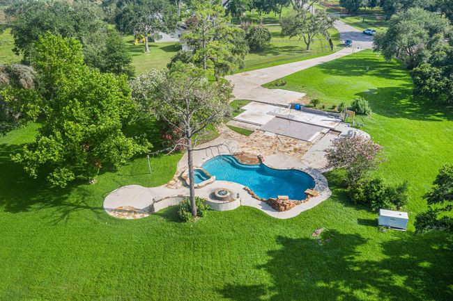 The centerpiece of the backyard is a custom-designed pool with a spa, fire pit, and natural stone accents, all surrounded by mature trees and beautiful landscape. | Image 7