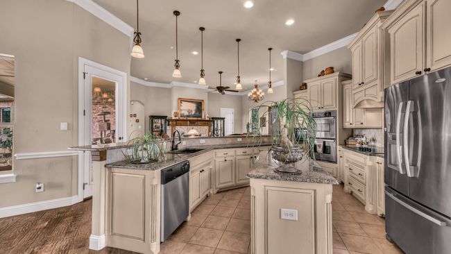 Kitchen with a sink, a kitchen island with sink, stainless steel appliances, cream cabinetry, and ornamental molding | Image 13