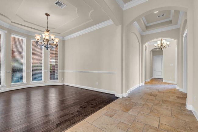 From the living and dining areas, the view of the front door showcases a grand and inviting entryway. Framed by architectural details the entrance creates a warm first impression and offers a clear sightline that enhances the home's open and airy feel. | Image 17