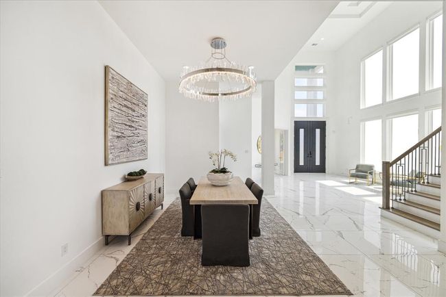 DINING ROOM: Designed with both style and functionality in mind, this space features clean lines and an open layout that seamlessly integrates with the rest of the home. Large windows flood the room with natural light, creating a bright and inviting ambiance perfect for any dining occasion. The neutral color palette and minimalist decor allow for personalization, making it easy to envision your own dining experiences here. | Image 6