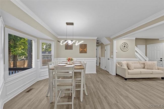 Dining space featuring ornamental molding, a wainscoted wall, a chandelier, a decorative wall, and light wood-style floors | Image 21