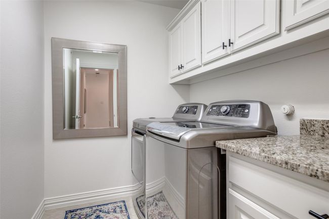 Laundry room featuring washing machine and clothes dryer, cabinet space, and light tile patterned floors | Image 19