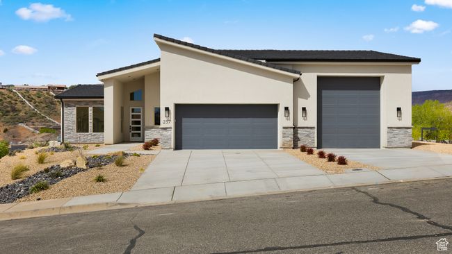 View of front of home with stone siding, driveway, stucco siding, and an attached garage | Image 25
