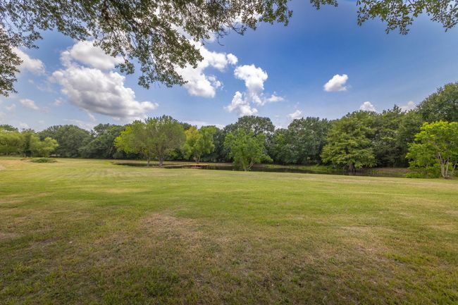 Experience tranquility in this spacious backyard, featuring lush greenery and serene views of the pond, perfect for relaxation or outdoor activities. | Image 37