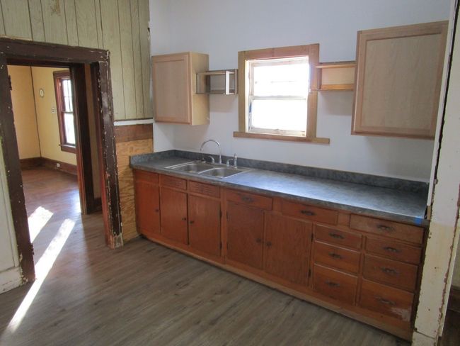 Kitchen with open shelves, a healthy amount of sunlight, wood finished floors, and a sink | Image 21