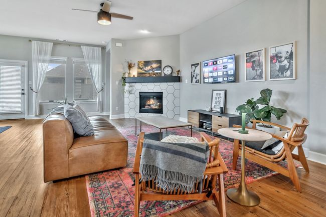 Living room with a stone fireplace, wood finished floors, and a ceiling fan | Image 12