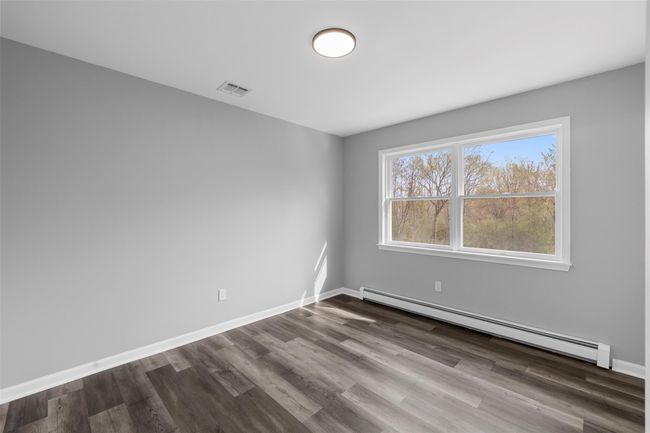 Unfurnished room featuring baseboards, visible vents, baseboard heating, and dark wood finished floors | Image 16