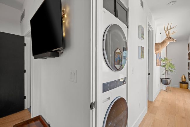 Washroom with stacked washer and clothes dryer and light wood-style flooring | Image 19