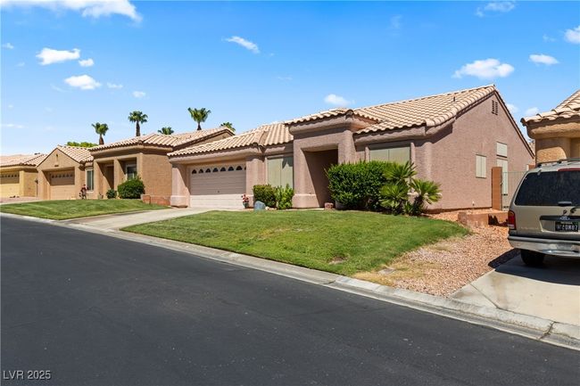 View of front facade featuring stucco siding, a front lawn, a garage, driveway, and a tiled roof | Image 49
