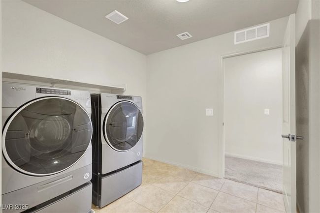 Washroom featuring washing machine and clothes dryer and light tile patterned floors | Image 42
