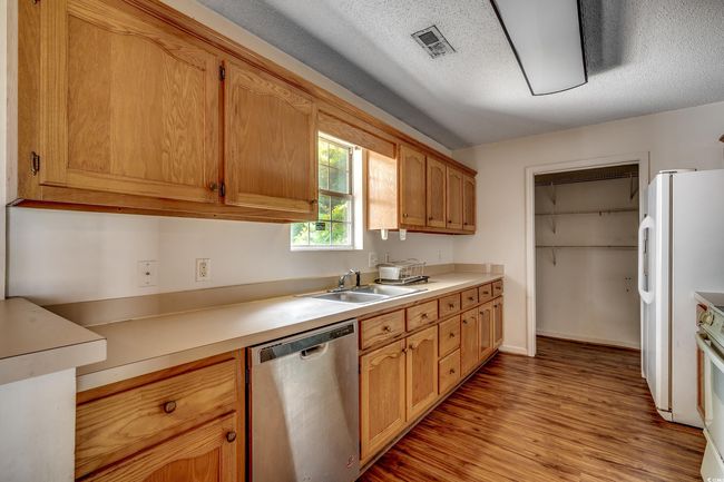 Kitchen with white appliances, light wood-style floors, light countertops, and a textured ceiling | Image 24