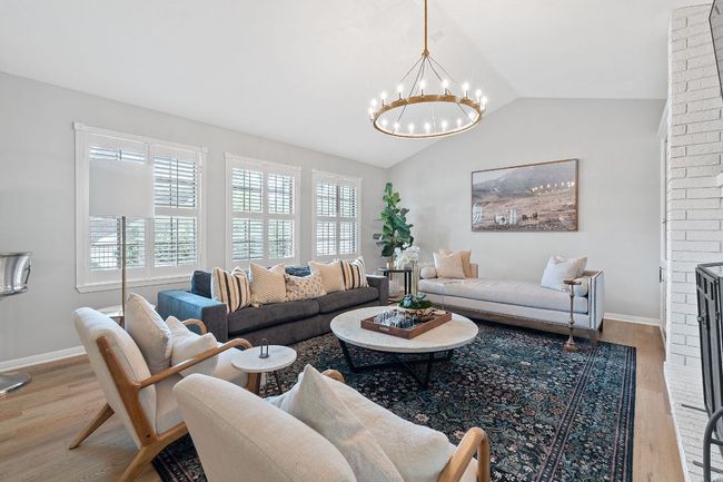 Living area featuring lofted ceiling, an inviting chandelier, a wealth of natural light, and wood finished floors | Image 5