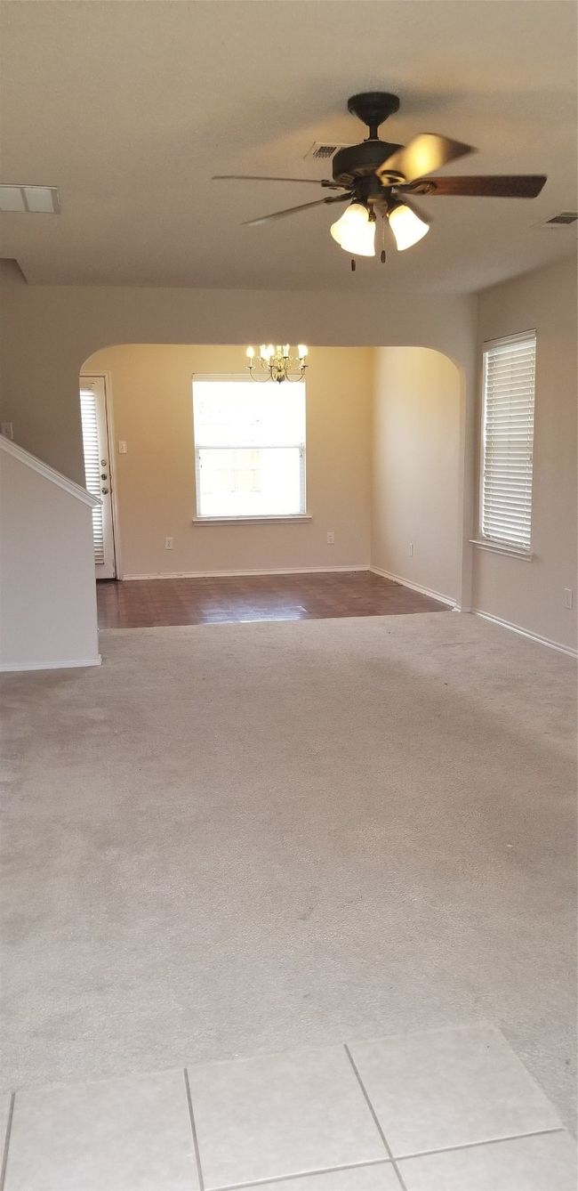 Empty room featuring arched walkways, ceiling fan, carpet, and a chandelier | Image 14