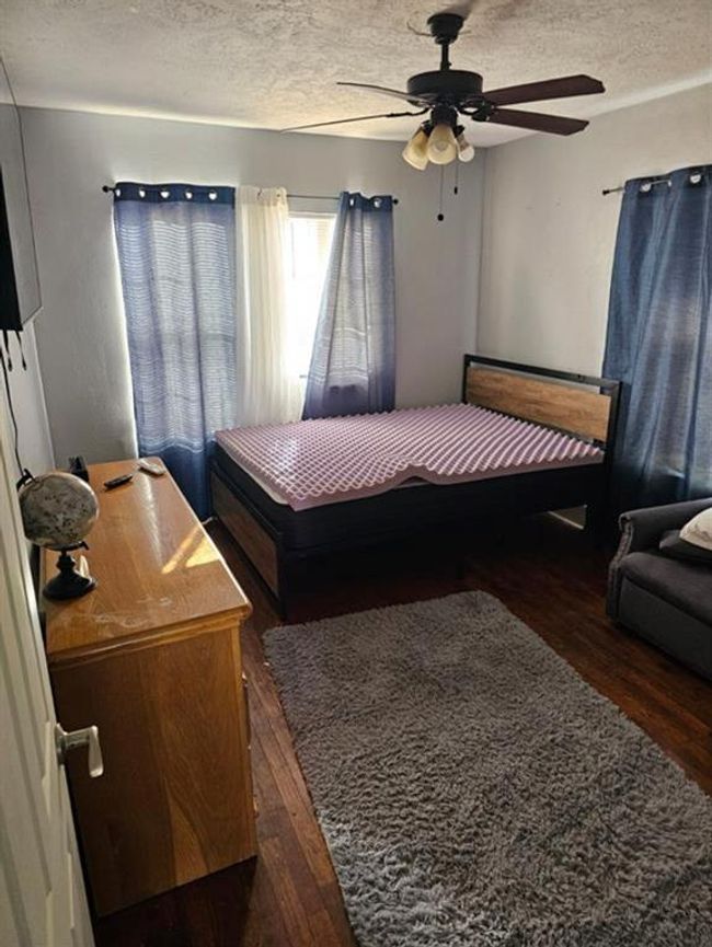 Spacious second bedroom with natural light, wood floors, and a ceiling fan, perfect for comfort and style. | Image 14