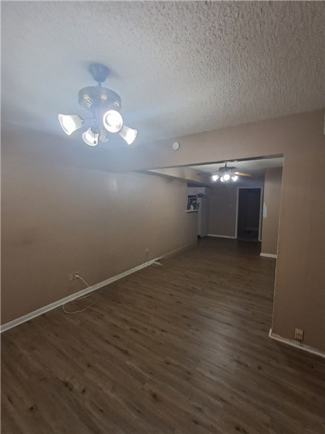 Empty room featuring dark wood-style flooring, a textured ceiling, ceiling fan, and a smoke detector | Image 12