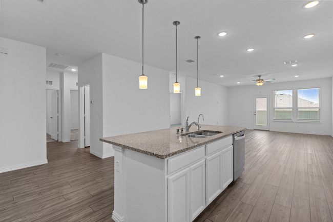 Kitchen featuring dishwasher, open floor plan, wood finished floors, a ceiling fan, and a center island with sink | Image 7