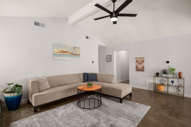 Living area featuring a ceiling fan, beamed ceiling, finished concrete flooring, baseboards, and high vaulted ceiling | Image 5