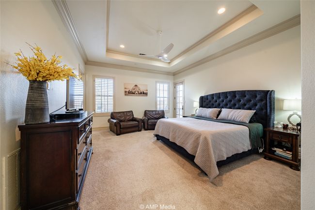 Bedroom with a tray ceiling, ceiling fan, light colored carpet, and ornamental molding | Image 20