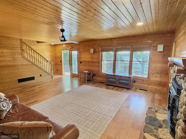 A sliding glass door opens to the expansive lakeside deck while the staircase leads to the upper level. | Image 13