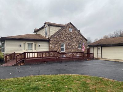 Rear view of property featuring an outbuilding, a garage, and a deck | Image 1