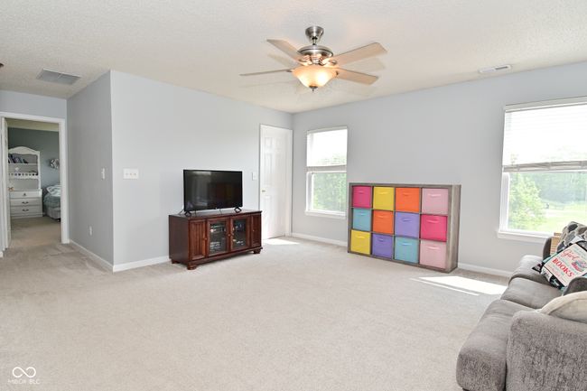 living area featuring light colored carpet, ceiling fan, healthy amount of natural light, baseboards, and a textured ceiling | Image 28